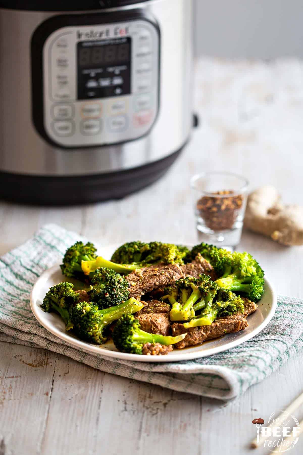 A plate of keto beef and broccoli next to the instant pot