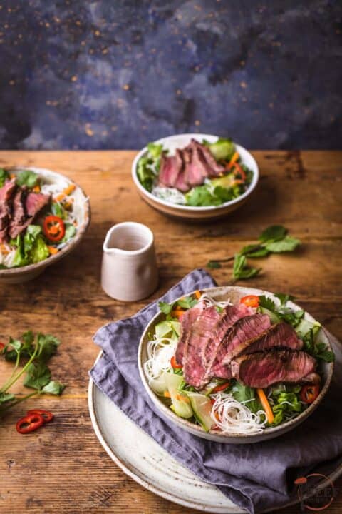 Three bowls of sirloin steak sliced over Vietnamese salad