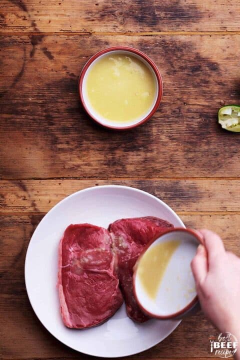 Pouring the steak marinade over rump steak