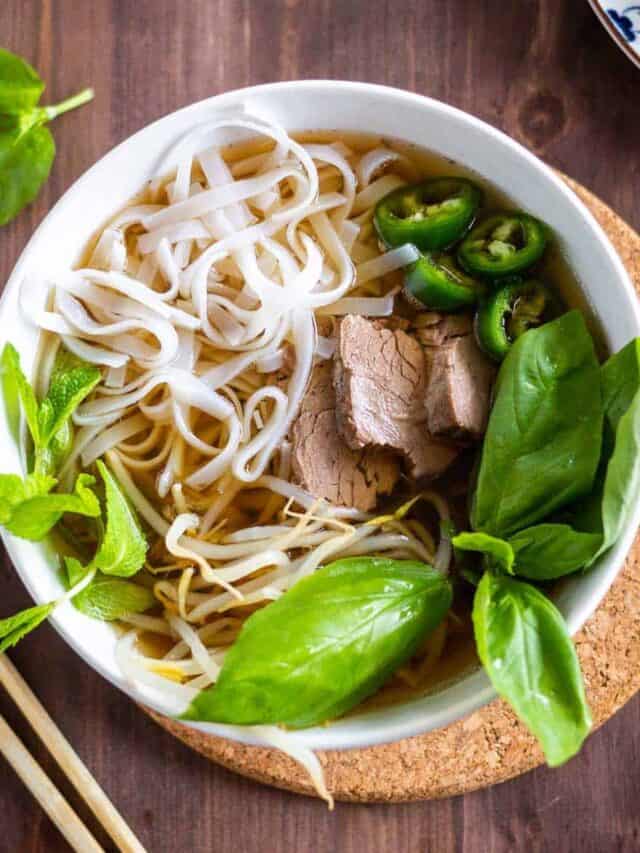 A white bowl of instant pot beef pho with chopsticks
