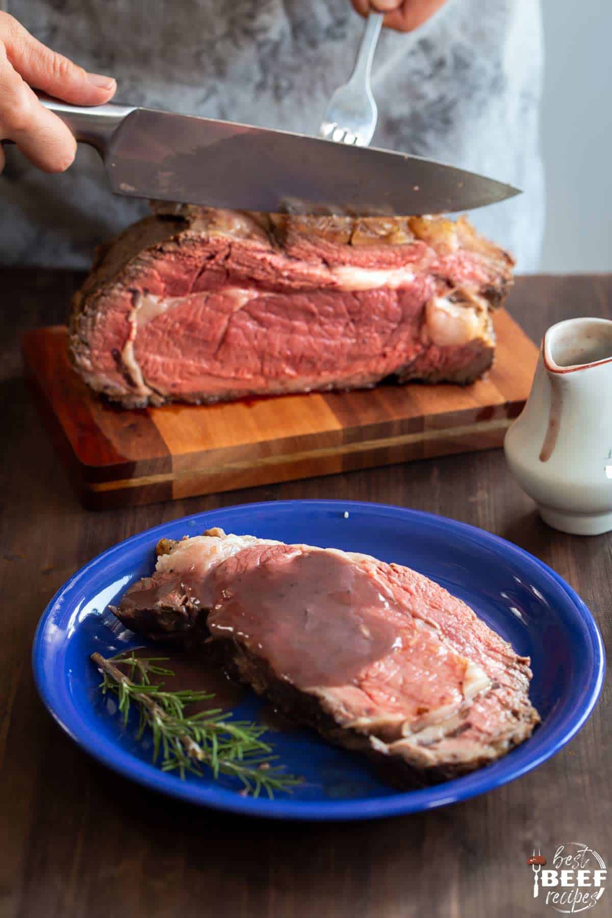 One blue plate of prime rib sliced in front of a whole Instant Pot Prime Rib roast