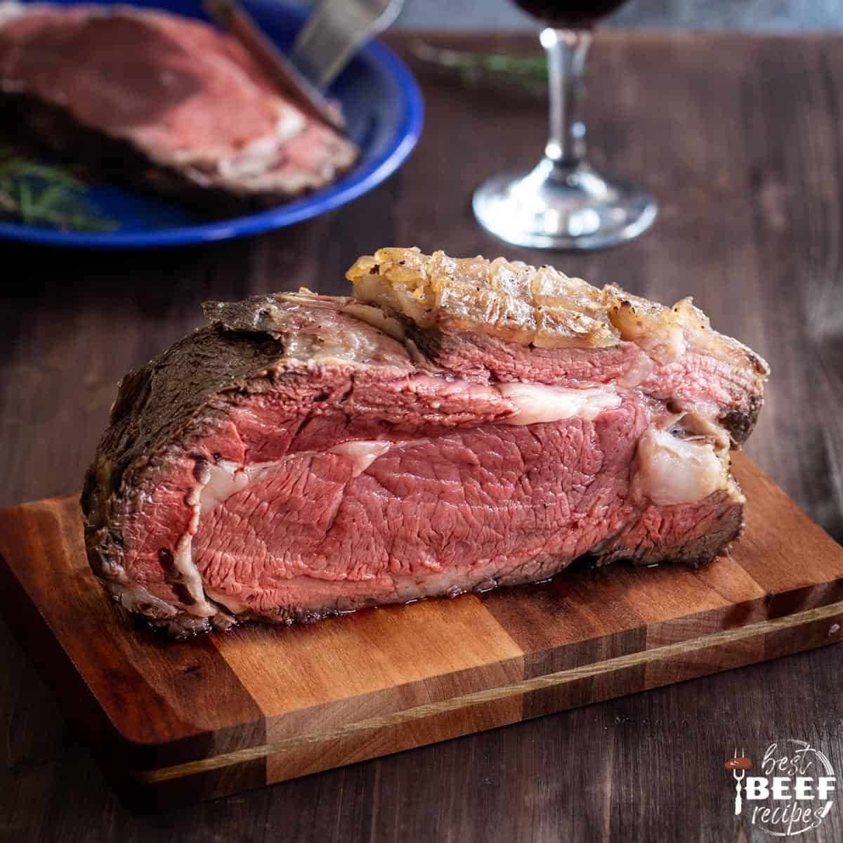 Instant pot prime rib roast on a cutting board in front of a plate of a slice of prime rib