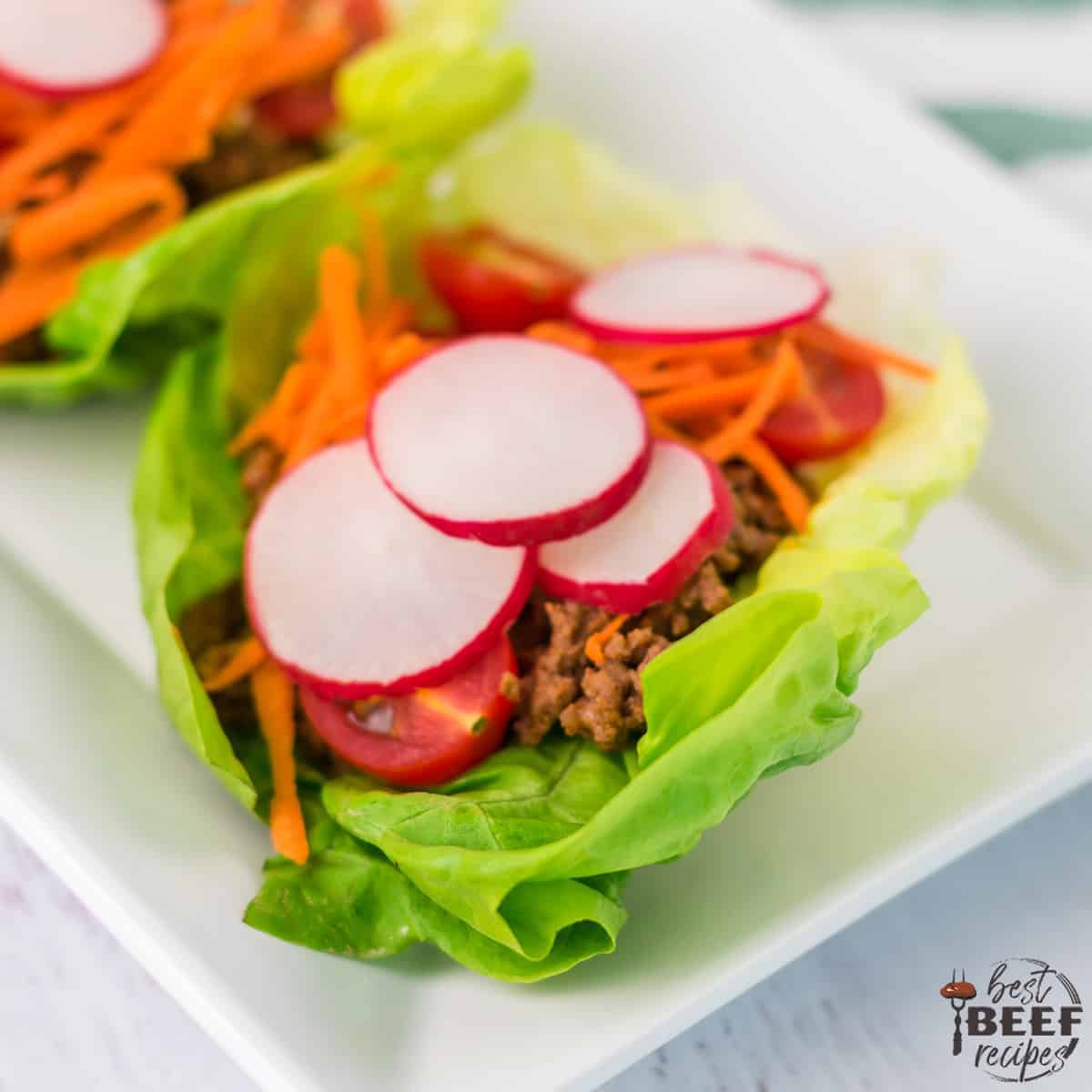 Portuguese Beef Lettuce Wraps Recipe on a white plate with radishes and carrots