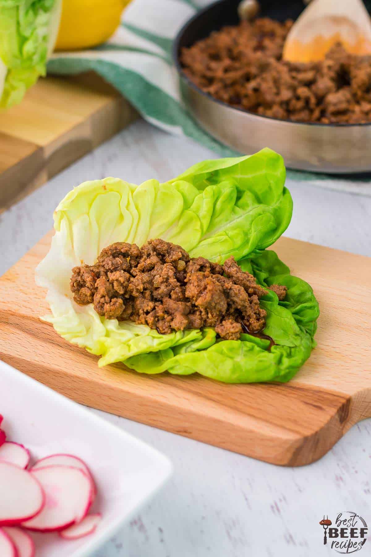 Filled beef lettuce wrap sitting on serving board