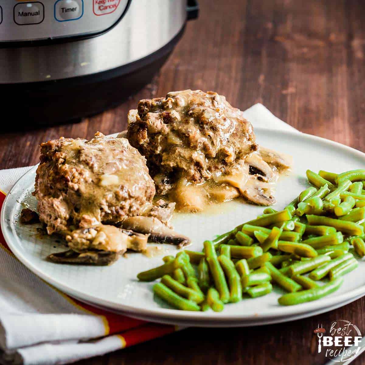 Two salisbury steaks on a white plate with green beans