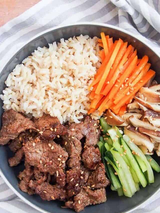 Korean beef bulgogi bowl recipe overhead shot with sliced cucumbers, carrots, and shiitake mushrooms over rice