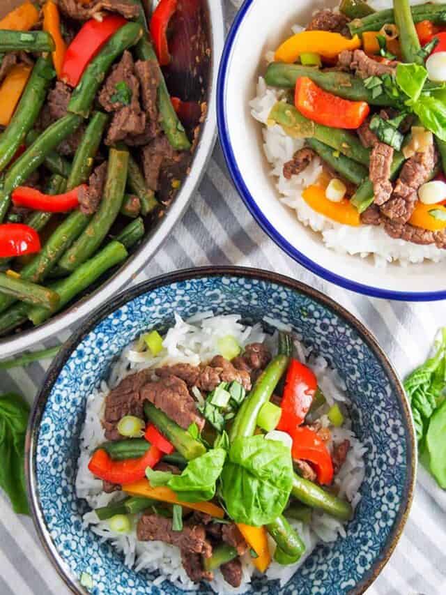 Two bowls of Asian beef stir fry with a pot of stir fry leftover