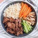 A bowl of Korean beef bulgogi with carrots, cucumbers, mushrooms and rice