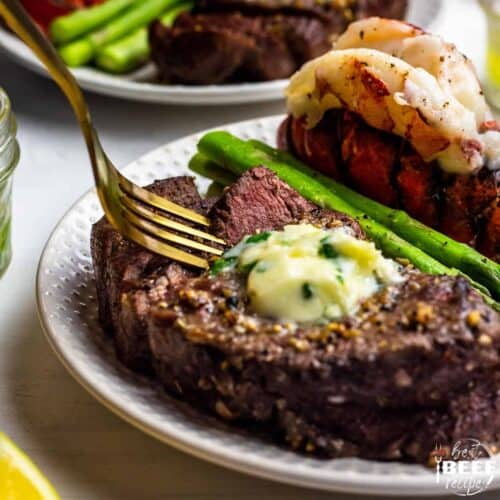 air fried steak on a plate with a fork, asparagus and lobster