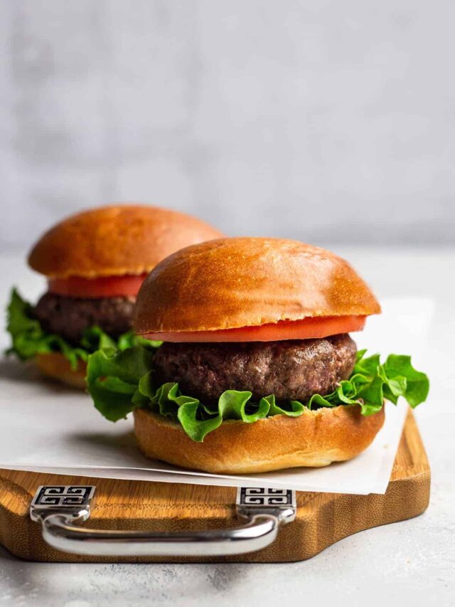 Two air fryer burgers on a wooden serving board