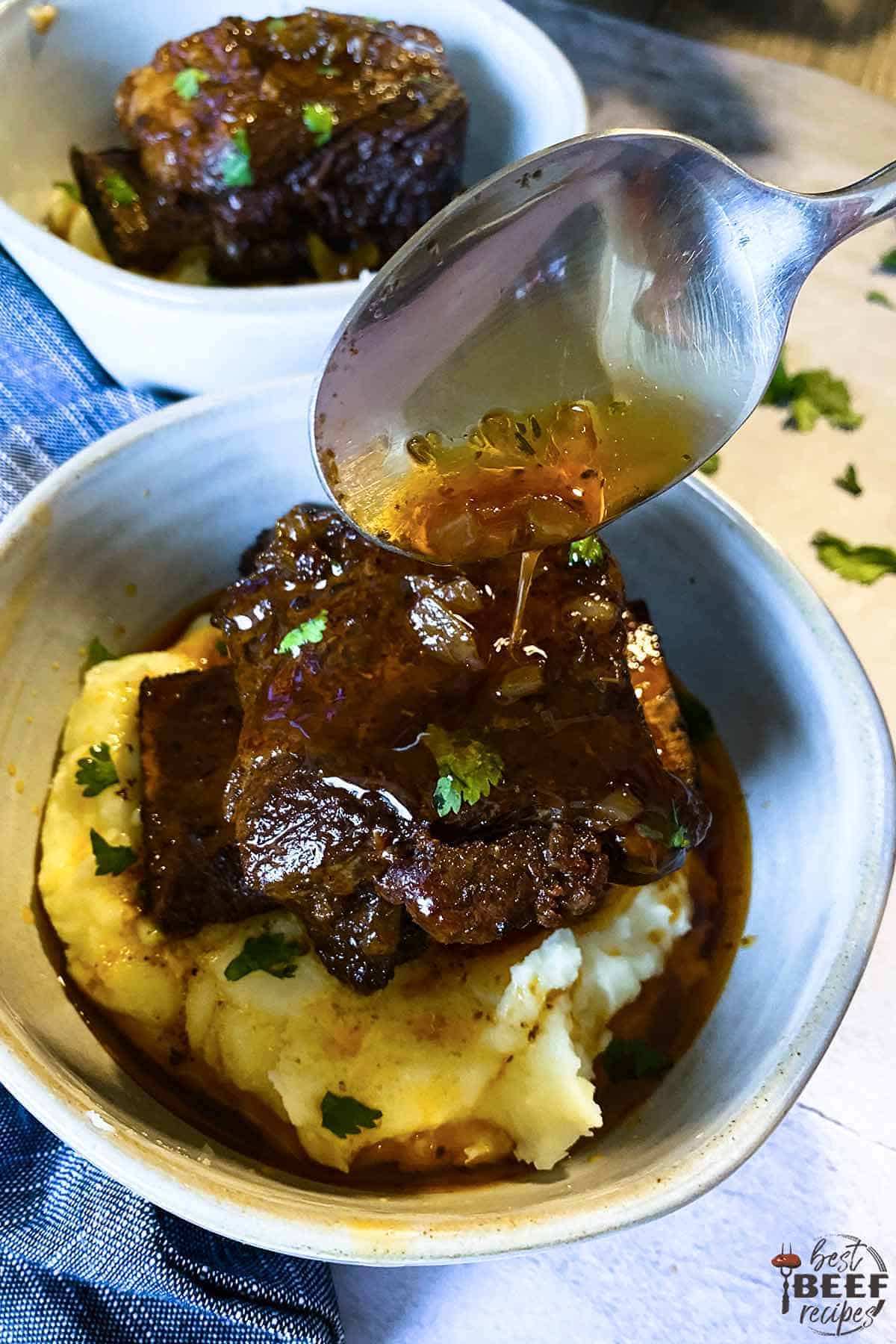 Dripping gravy over Slow cooker short ribs over mashed potatoes in a bowl