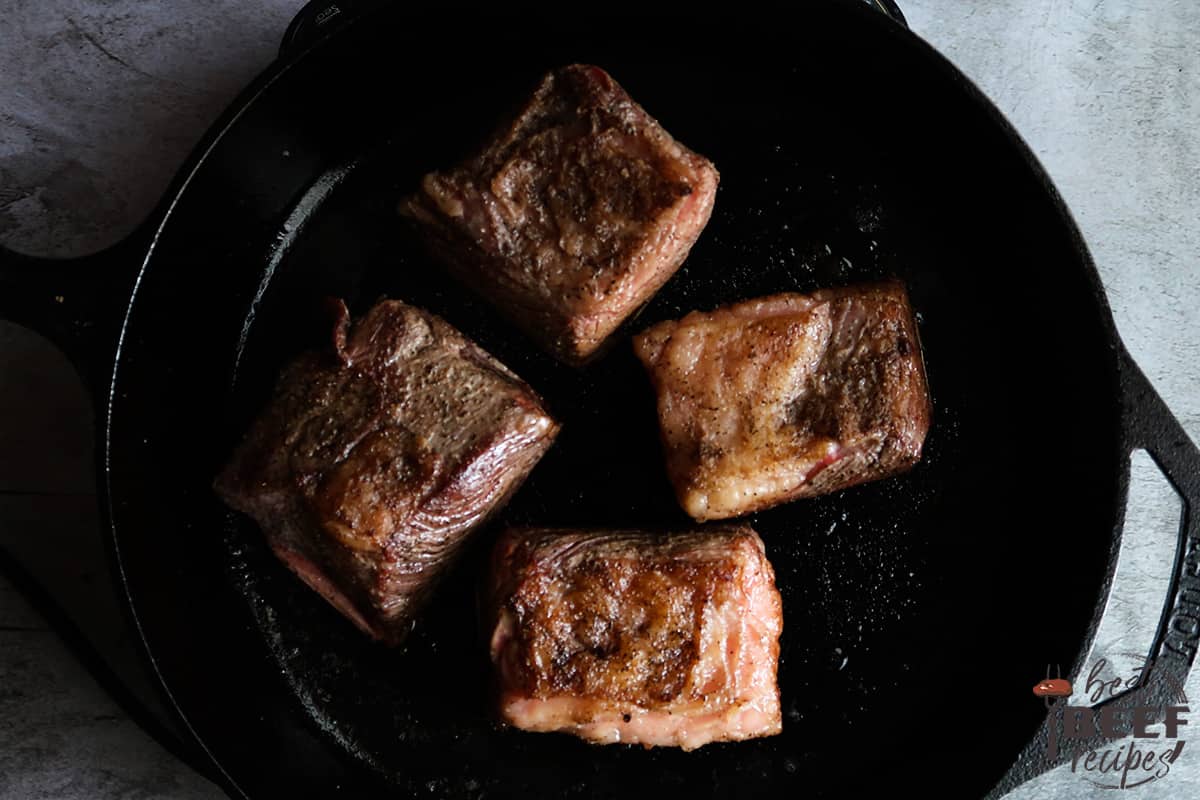 Beef ribs searing in cast iron pan