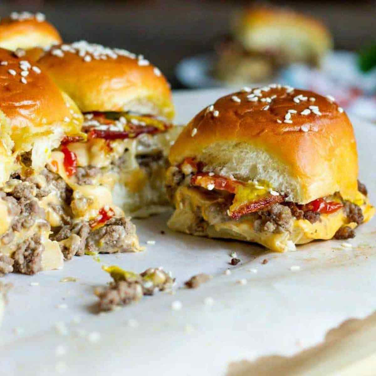 Mini bacon cheeseburger sliders on a sheet of parchment paper