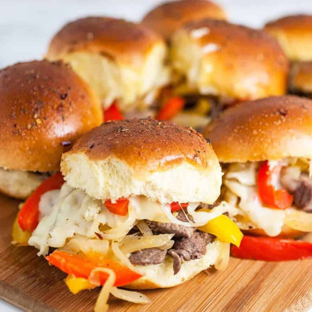 Philly cheesesteak sliders on a wooden board up close