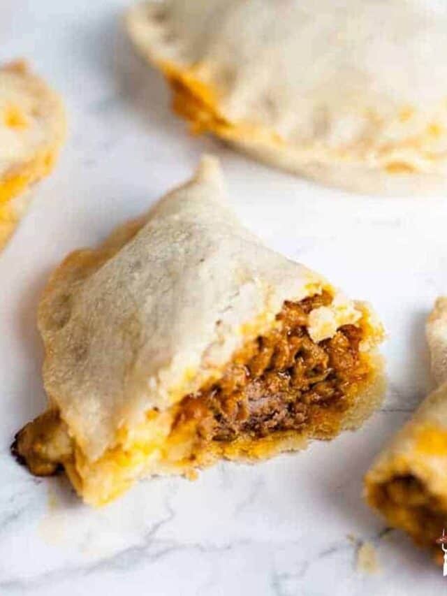Close up of pastelillos de carne with one split open to show the beef filling