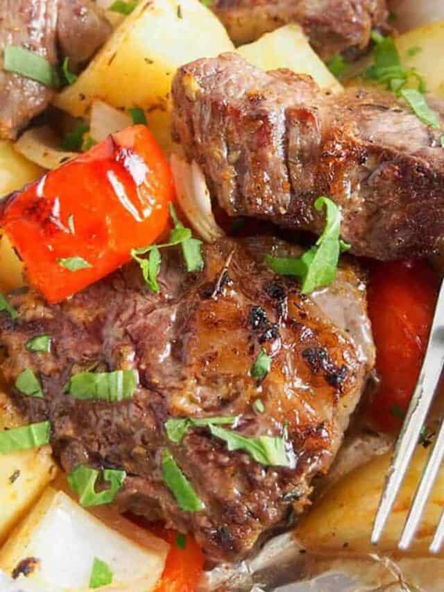 Close up of cooked steak, peppers, and potatoes next to a fork