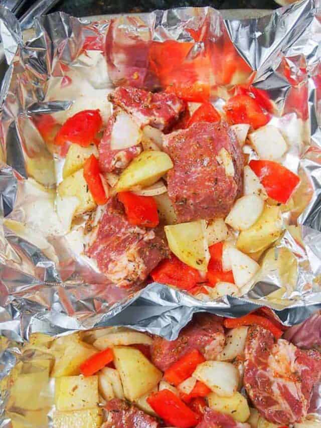Diced steak, peppers, potatoes, and onions in foil, ready to wrap into steak foil packs