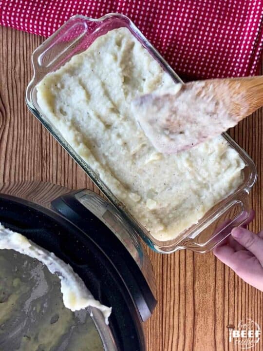 Spreading mashed potatoes over Shepherd's Pie filling in a casserole dish