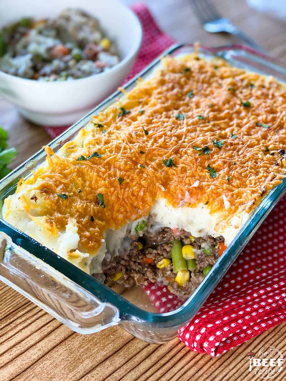 Shepherd's Pie in a casserole dish with a portion served in a white bowl