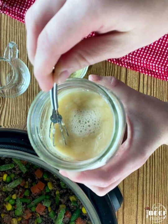 Stirring together butter, flour, and beef broth in a jar with a small whisk