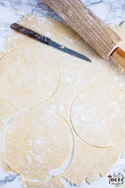 cutting rounds out of empanada dough with a rolling pin to the side