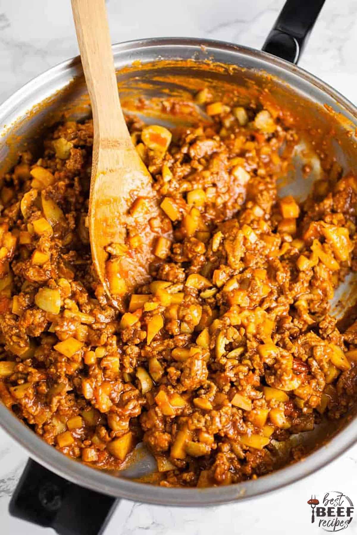 Empanada filling in a skillet with a wooden spoon