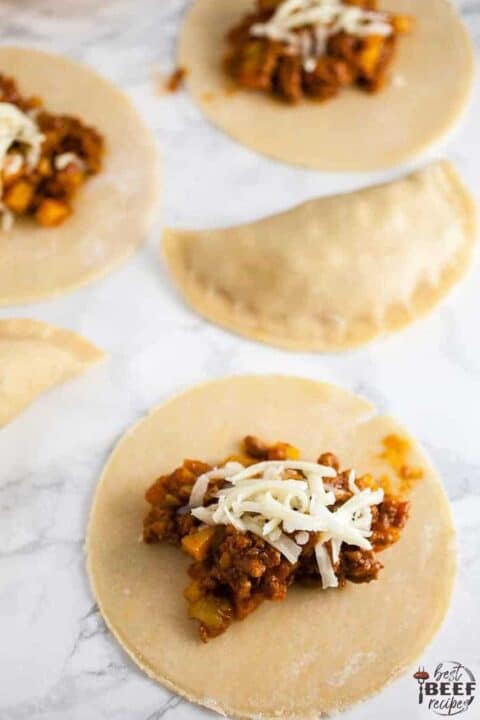 Filling empanada discs with cheese and beef