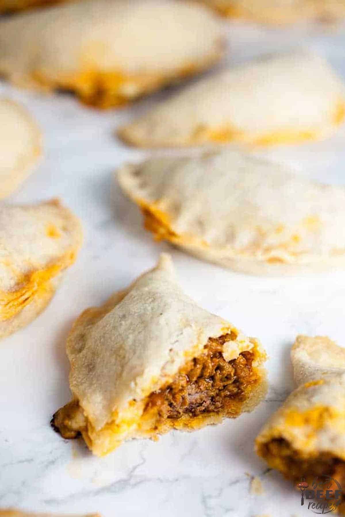 A baked empanada split open in front of other empanadas