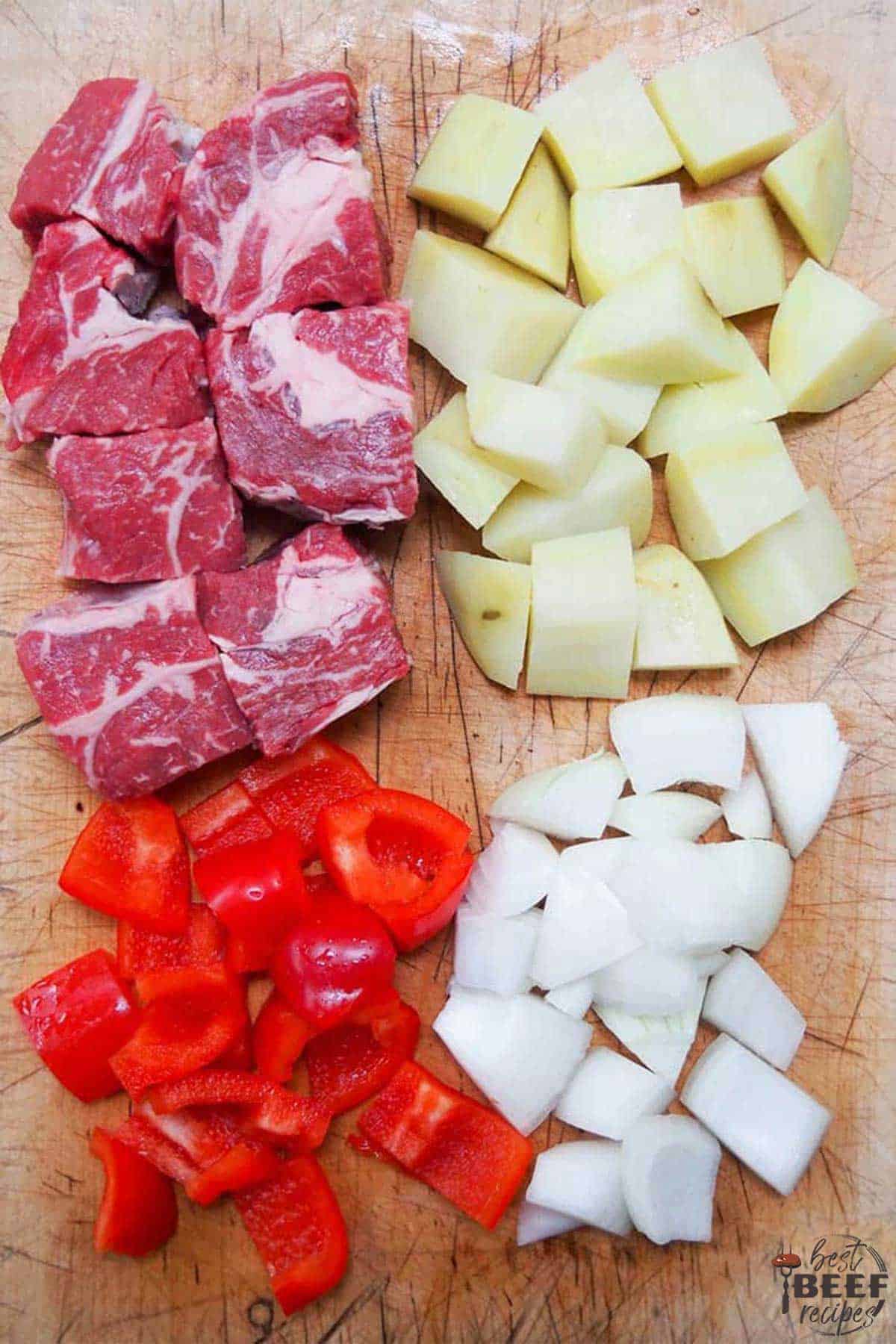 Diced steak, potatoes, peppers, and onions on a cutting board