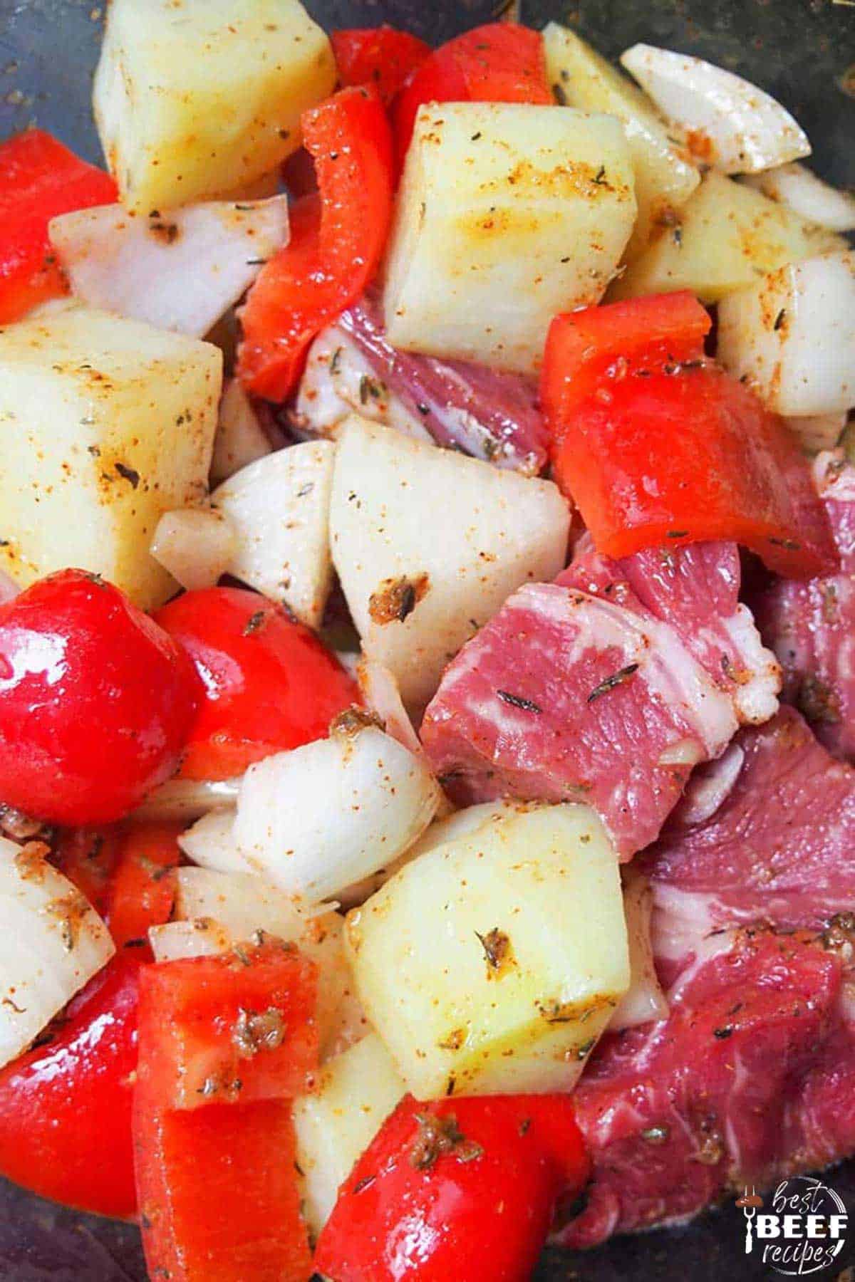 Diced steak, potatoes, peppers, and onions up close coated in oil
