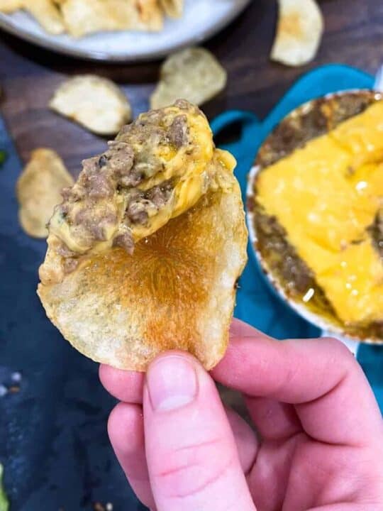 Dipping a chip into the instant pot philly cheese steak dip with cheese on top