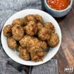 Close up of instant pot meatballs on a white dish with a side of dipping sauce