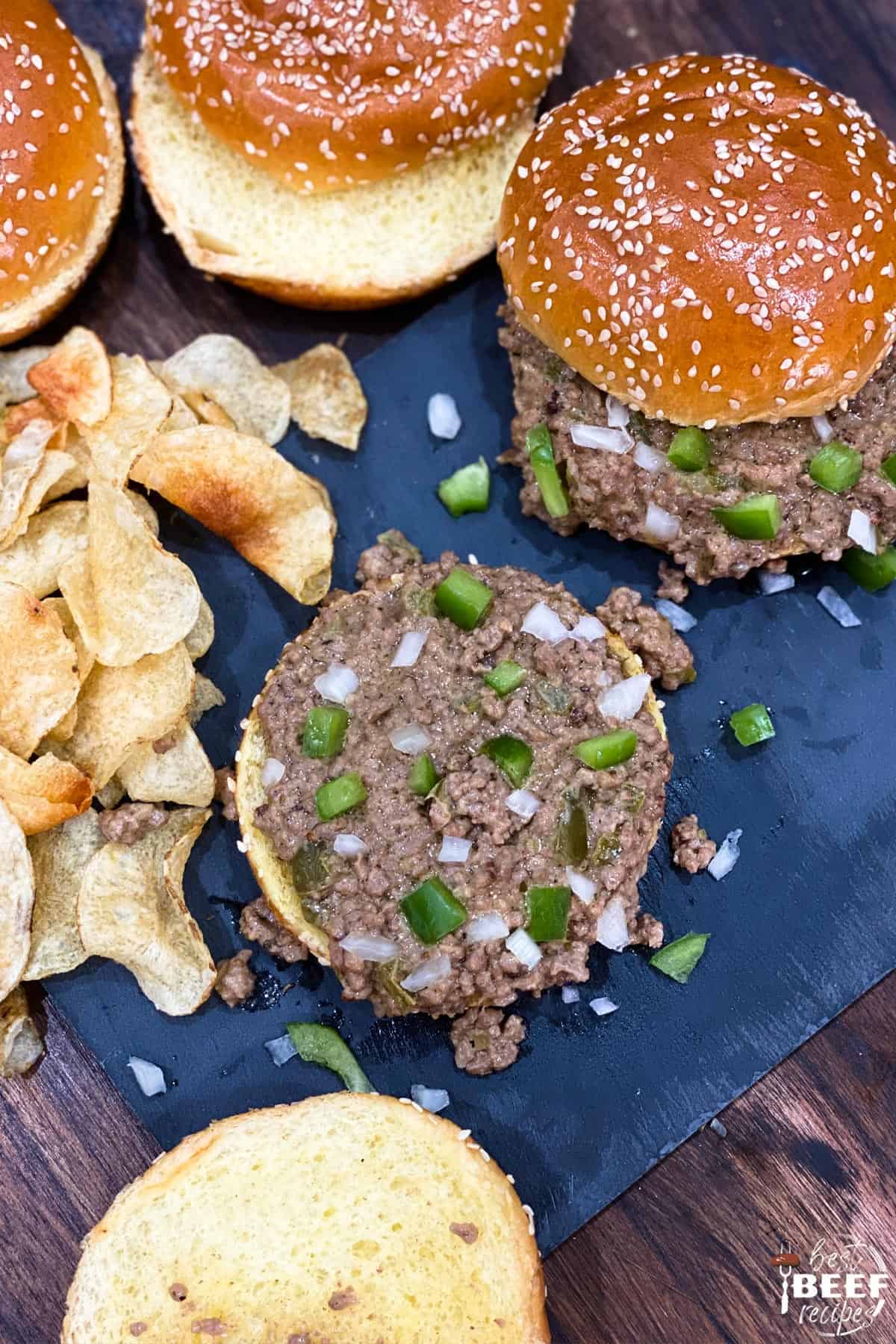 Top-down view of Instant pot philly cheesesteak sloppy joes next to potato chips on a black surface