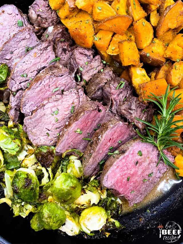 Close up of sous vide tenderloin sliced next to brussels sprouts and sweet potatoes in a skillet