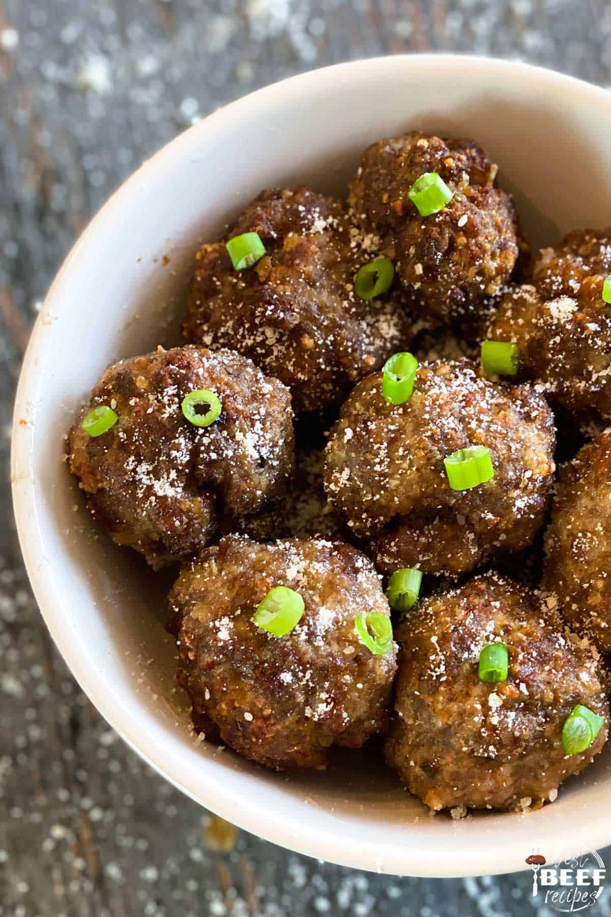 Air fryer meatballs with green onion slices in a white bowl