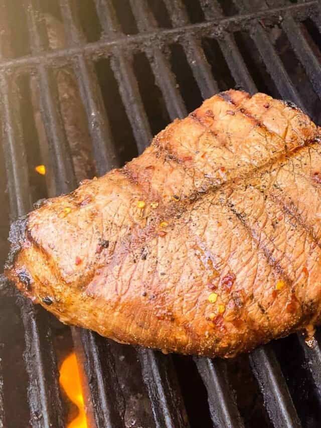 Grilled london broil on the grill with a spatula