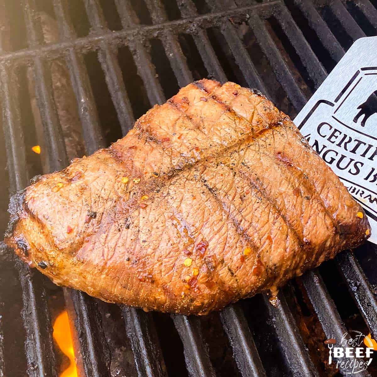 Grilled london broil on the grill with a spatula