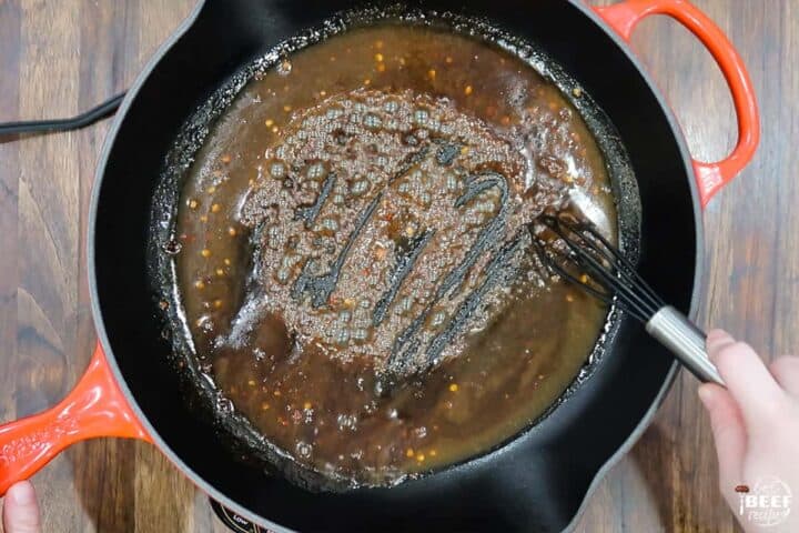 Cooking the marinade down into a sauce in a skillet with a whisk