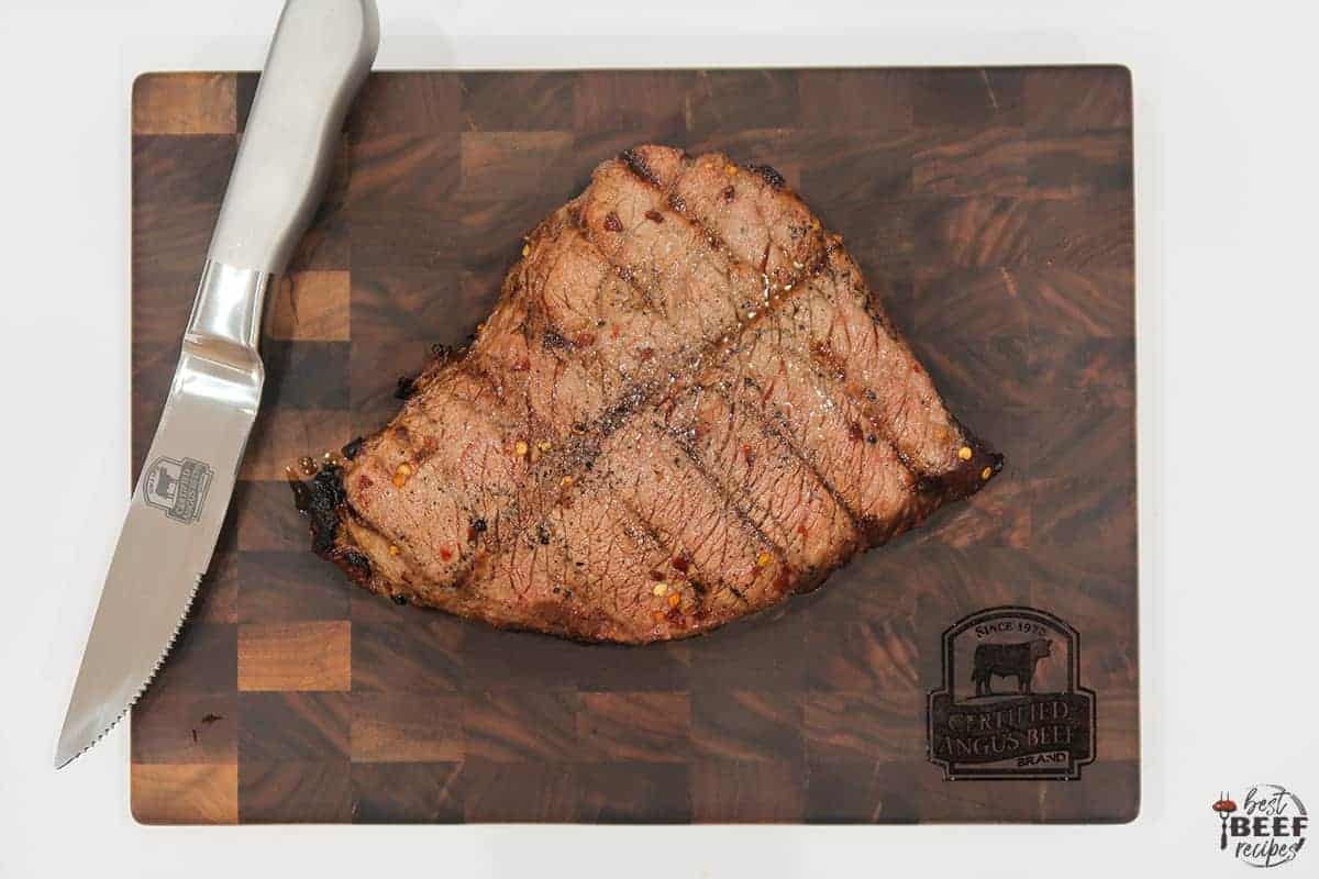 A grilled london broil ready to be sliced on a cutting board