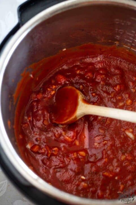 Stirring tomato sauce into instant pot with onions and garlic