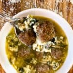 a bowl of Instant Pot Italian Wedding Soup with a spoonful of soup and two meatballs