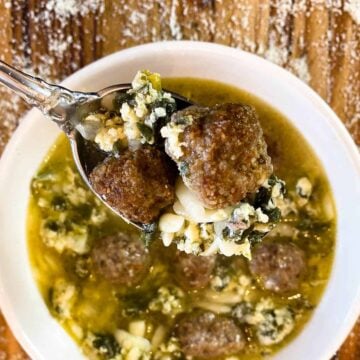 a bowl of Instant Pot Italian Wedding Soup with a spoonful of soup and two meatballs