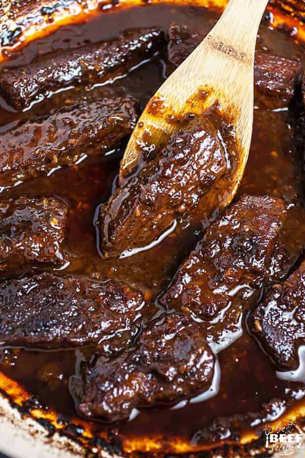 Cooked Korean beef short ribs with a wooden spoon in a Dutch oven