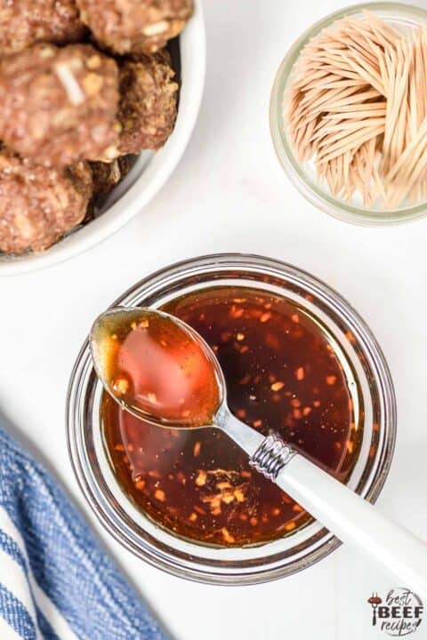 Honey sriracha sauce with a spoon in a glass jar