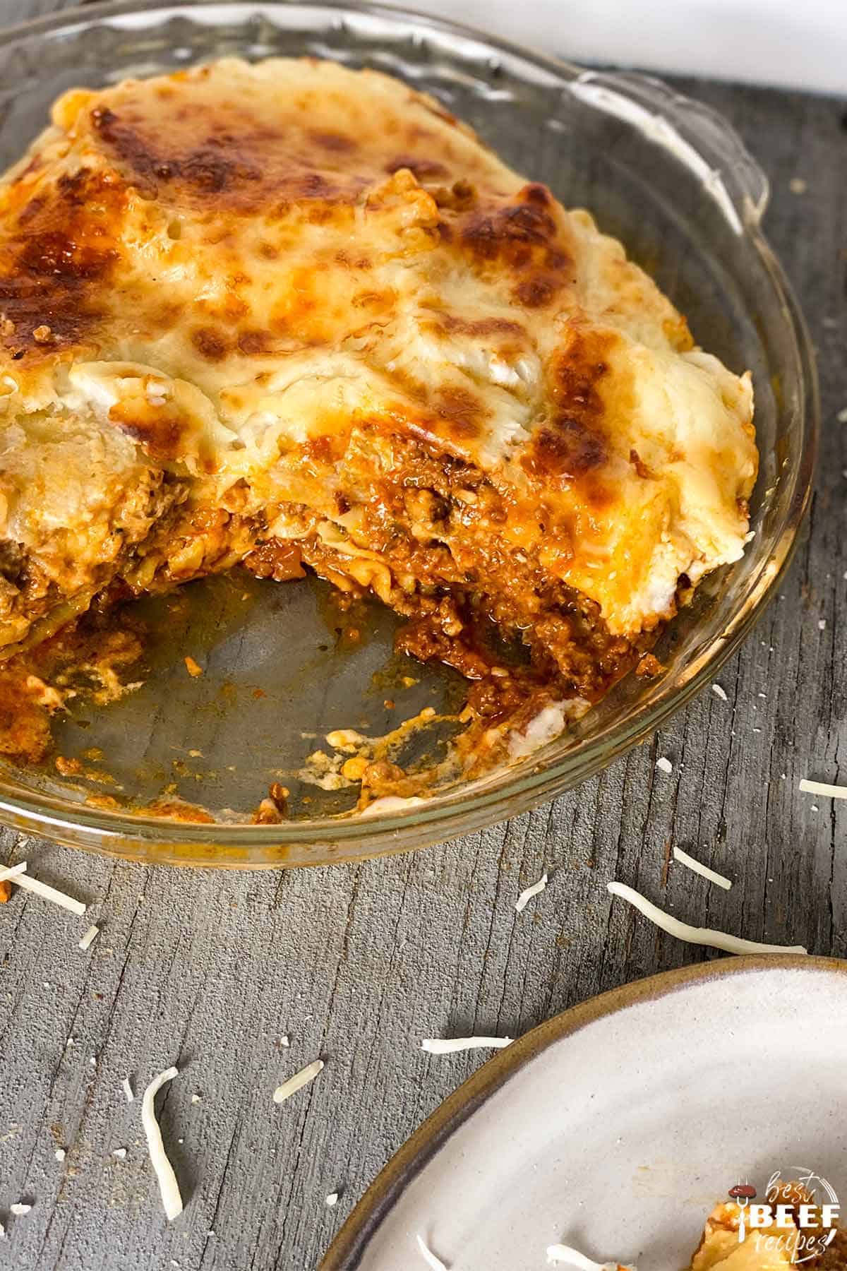 Beef lasagna in a glass dish with a slice missing
