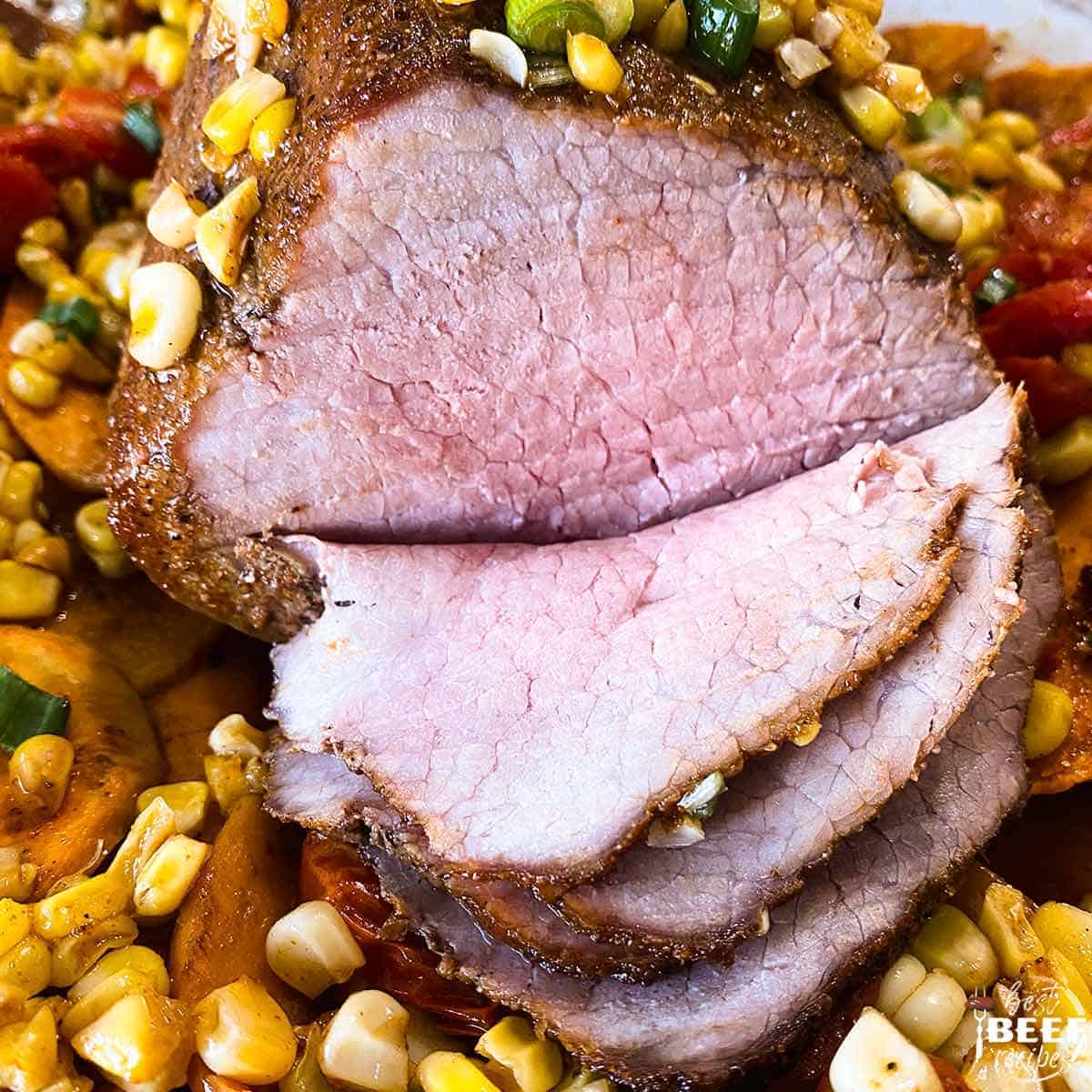 eye round roast cut into slices over corn and tomatoes