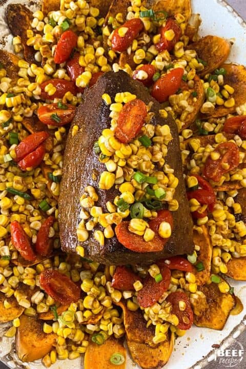 Eye round roast on a bed of sweet potatoes with corn and tomatoes