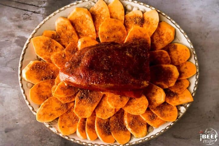 Eye of round roast over a bed of sweet potatoes with seasoning