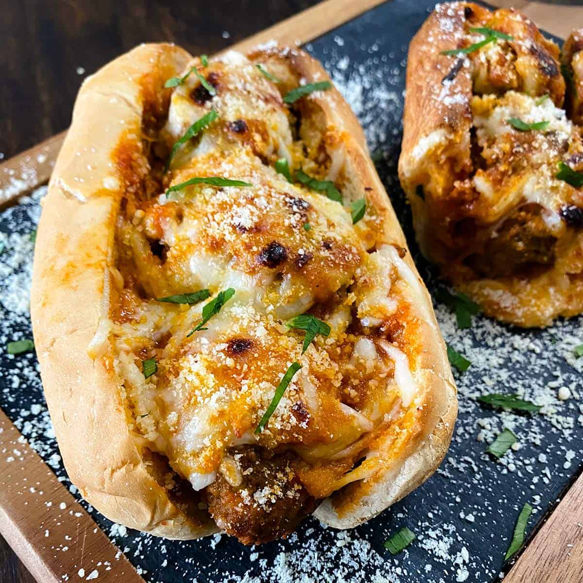 Two meatball subs close up on a serving board