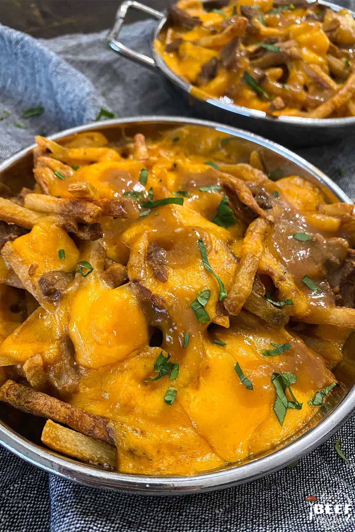Close up of poutine in a metal baking dish